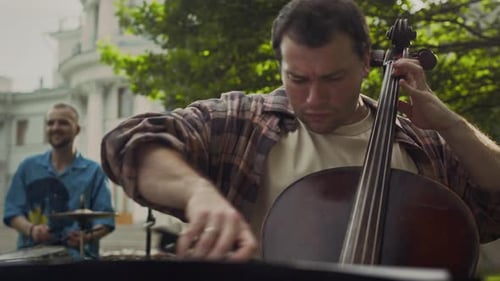 Drummer and Cellist Playing Music on Outdoor Concert in Park