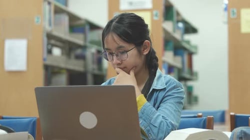 Young female student studying on her laptop computer in library