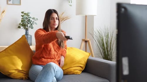 Young Woman Relaxing on Sofa with TV Remote