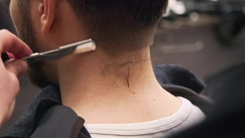 O uso de um barbeiro de barbear corta manualmente os cabelos restantes na nuca do cliente