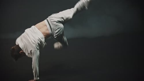 Young Man Training His Breakdancing Tricks in the Dark Studio