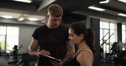 Personal Trainer Discussing Fitness Plan with Woman at Gym