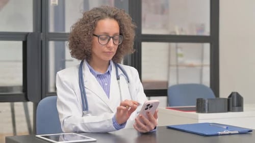 Hispanic Female Doctor Using Smartphone in Hospital