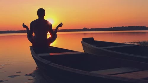 Person Meditating in Boat at Peaceful Sunset