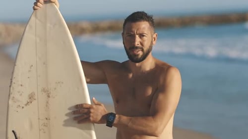 Smiling Surfer on Beach with Surfboard