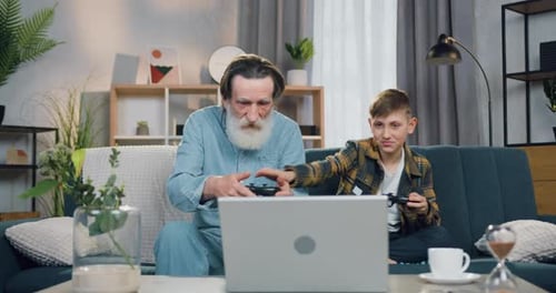 Grandfather and Grandson Play Video Games Together Indoors