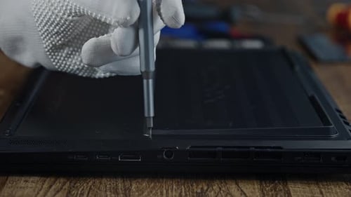 Eine Person verwendet einen Schraubenzieher, um eine Schraube von einem Laptop zu entfernen