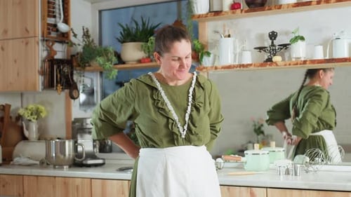 Woman Puts on Apron in Cozy Kitchen