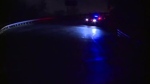 POLICE CAR DRIVING WITH SIRENS AT NIGHT ON RURAL ROAD
