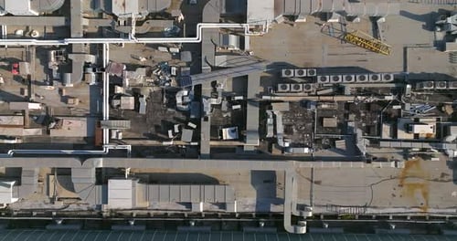 Industrial building rooftops with vents and pipes lined across, Top down view