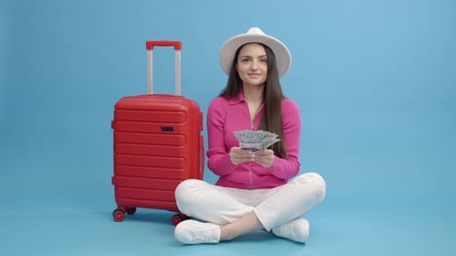 Woman Planning Vacation With Money Next To Suitcase