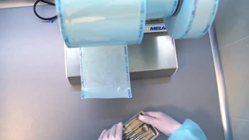 Hände in Handschuhen nehmen ein kleines Metalltablett mit Instrumenten für die Zahnpflegeuntersuchung.