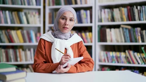 Webcam view Muslim female student in hijab with a notebook listens to online e-learning by video