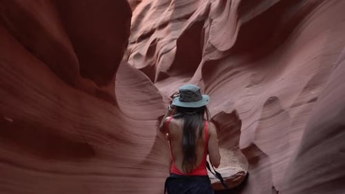 Rücken einer jungen Frau mit Fotokamera, die in einer schmalen Sandsteinschlucht spaziert, atemberaubende Landschaft a