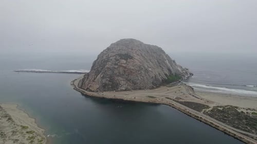 Aerial View Of Morro Rock And Beach In Morning Fog. Dolly Forward