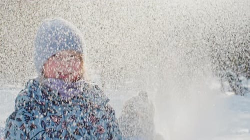 Slowmo-Porträt eines süßen kleinen Mädchens, das unter fallendem Schnee im Park posiert