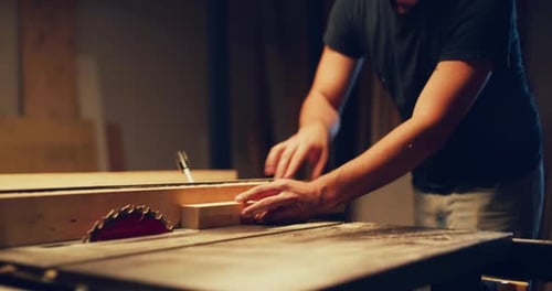 Cabinetmaker skillfully uses table saw to precisely cut wood in workshop