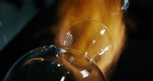 Slow motion macro of glass blower working with flame on a handmade art piece of glass from preciou