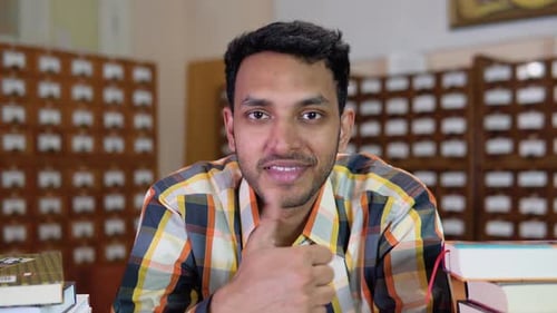 Portrait of Young Positive Indian Student in University Library
