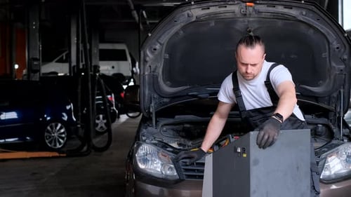 Mann arbeitet an einem Auto in der Garagenhaube und öffnet Autoreparaturen