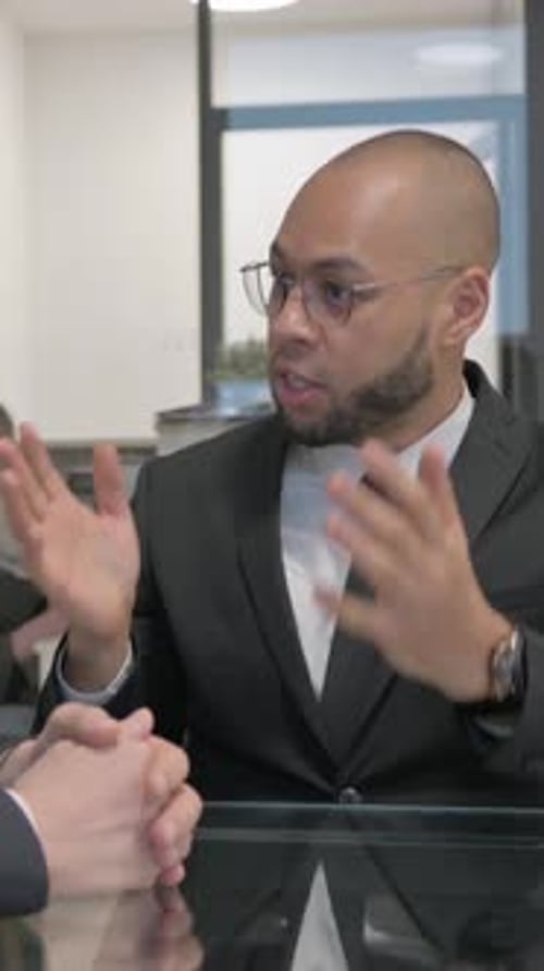 Man in suit speaking to colleague at desk