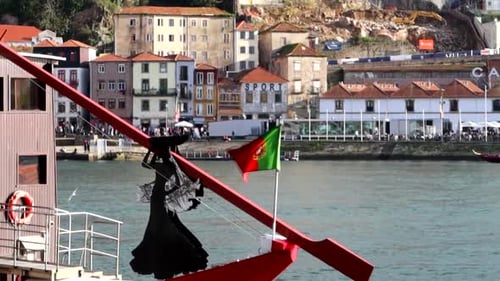 Portuguese flag at the stern of Rabelo boat next to a woman silhouette, Porto