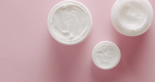 Jars of cream on pink surface
