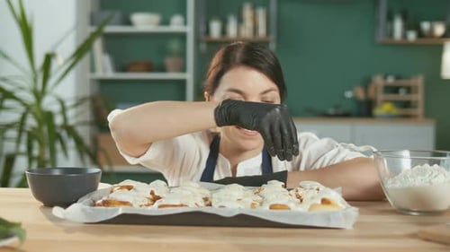 Closeup A Contented Female Pastry Chef Sprinkles Almonds on the Glazed Buns