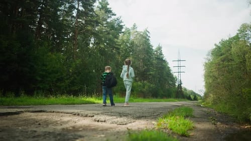 Boy with Backpack Walking with Sister on Forest Path Under Power Lines