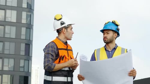 Construction Workers Reviewing Plans at Building Site
