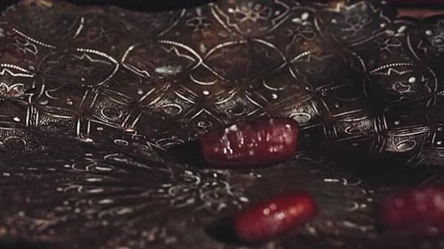 Beautiful shiny dried dates roll one by one into a dish. Slow motion shot.