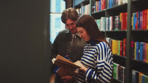 Students Sharing Book in Library