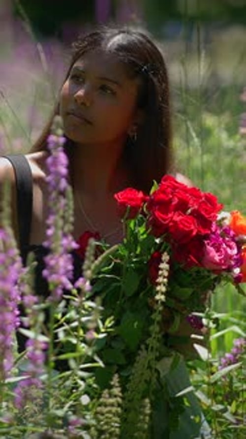 A Young Woman Holding a Beautiful and Vibrant Bouquet Surrounded By Colorful Wildflowers