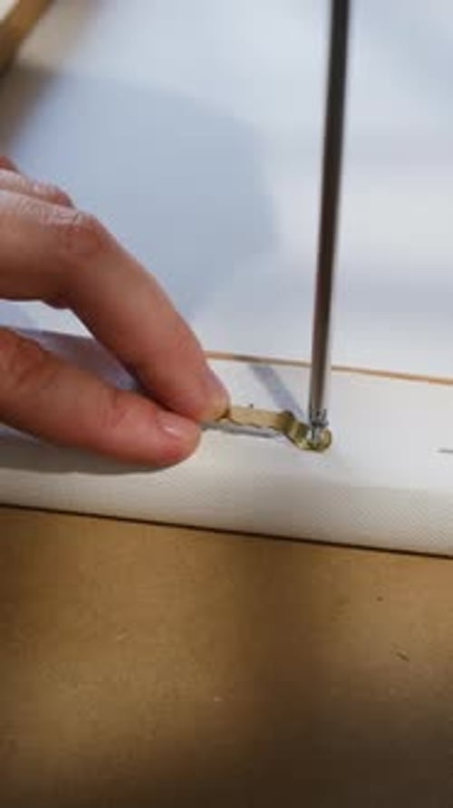 Hand Attaching Metal Bracket to Canvas with Screwdriver