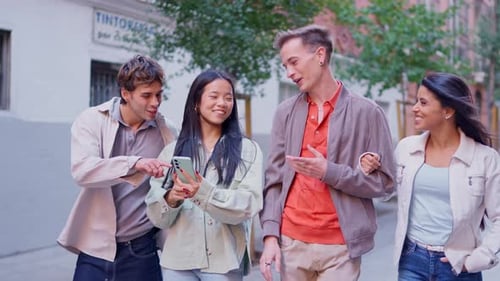 Friends walking on city street looking at smartphone