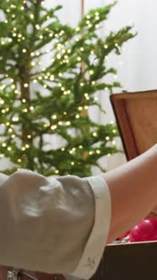 Woman Preparing Christmas Decorations in Box by Tree