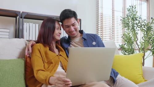 Couple Relaxing At Home Using Laptop