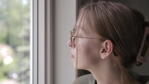 Woman with Glasses Looks Out Window Indoors