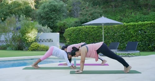 Hembras diversas con jóvenes que siguen las señales del líder, haciendo fluir vinyasa para mantener la salud junto a la piscina sobre colchonetas