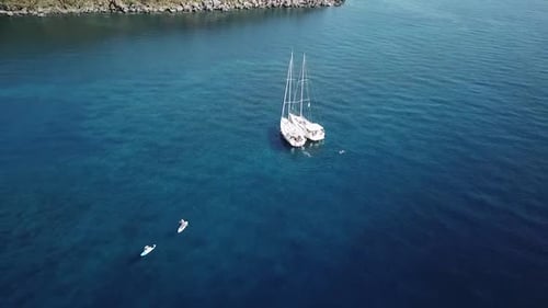 Aerial view of the boat on anchor and people on SUP in Italy, Sicily, Volcano island