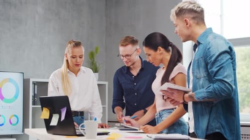 Team of Young Startupers is Working at the Table in the Office Discussing the Strategy and