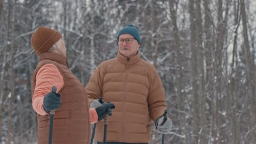 Active Old Couple Nordic Walking in Winter Forest