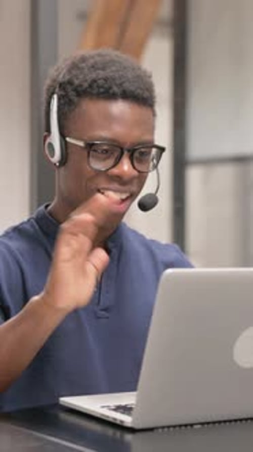 Young Man with Headset Working on Laptop