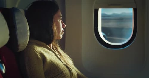 Cinematic shot of young woman sitting in cabin and looking out of window