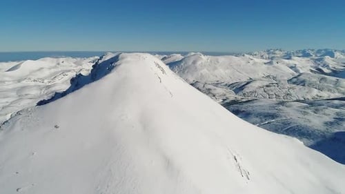Vue aérienne à couper le souffle d'un pic isolé recouvert de neige, entouré par les majestueuses montagnes de Pi