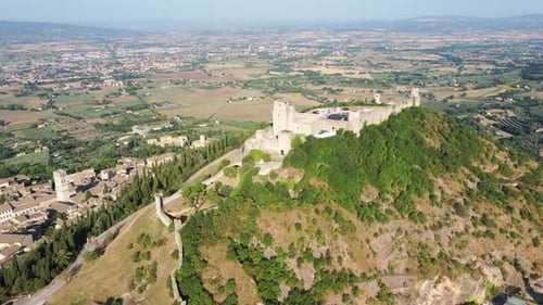 Luftaufnahme der Kathedralen im Stadtzentrum von Assisi, der mittelalterlichen Festung Rocca Maggiore und der Weinberge an der