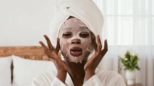 Woman Applying Sheet Mask in Bright Bedroom