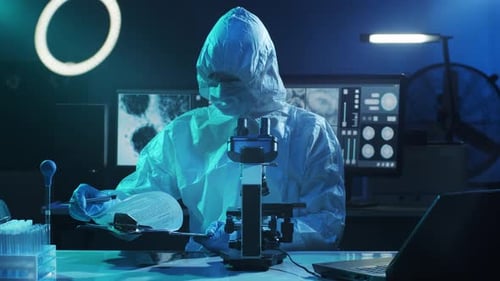 Scientist Working with Microscope in Dark Blue Lab