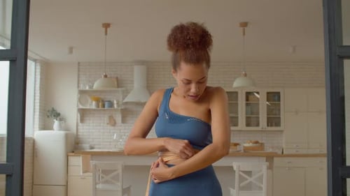 Belle femme africaine vérifiant le tour de taille avec un ruban à mesurer après un régime