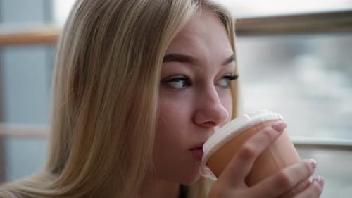 Closeup of Woman Gazing Thoughtfully While Sipping Coffee in a Cozy Cafe